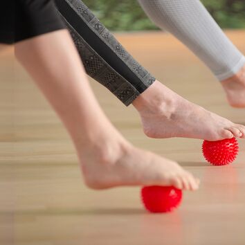 nackte Füße werden mit einem Igelball massiert